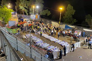Rescue and medical personnel next to covered dead bodies on Mount Meron