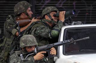 Army soldiers take position during an operation at Morro do Alemao slum in Rio de Janeiro