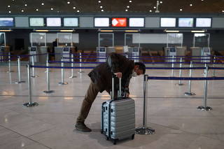 A passenger waits for check-in in the departures area of the Terminal 2E at Charles-de-Gaulle airport in Roissy
