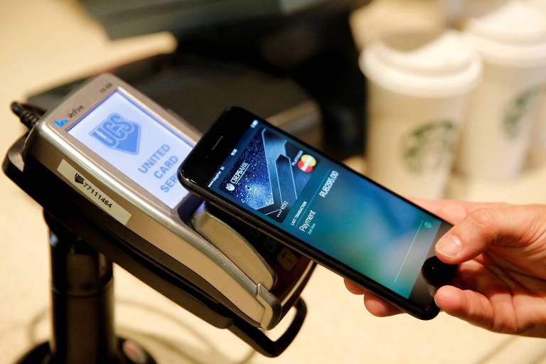 Homem usa iPhone 7 para demonstrar pagamento por aproximação feito por celular, a partir de carteira digital