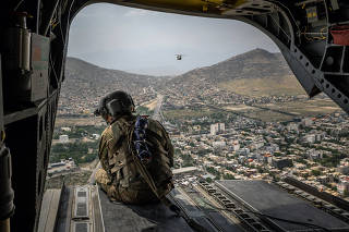 A U.S. soldier aboard a Chinook helicopter over Kabul, Afghanistan, on Sunday, May 2, 2021. (Jim Huylebroek/The New York Times)