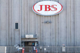 FILE PHOTO: Employees walk around with face masks at the JBS USA meat packing plant in Greeley, Colorado