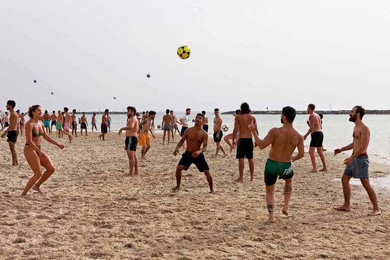 Pessoas jogam futevôlei em praia de Tel Aviv depois de o governo anunciar que uso de máscaras ao ar livre não é mais necessário 