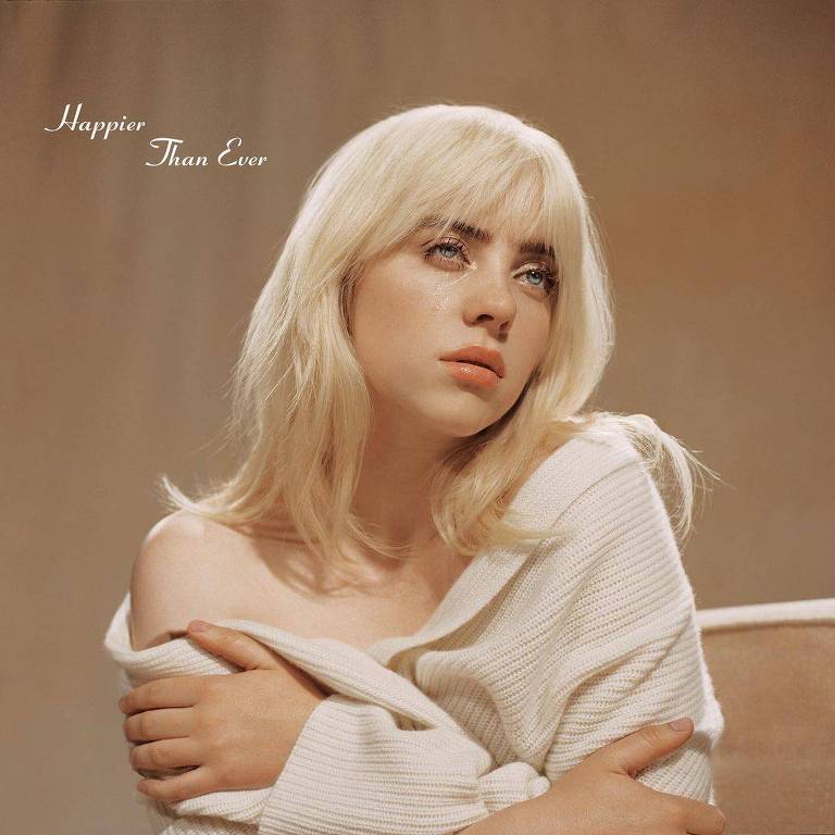 mulher branca de cabelos loiros longos levemente encaracolados chorando e usando blusa de lã branca levemente aberta