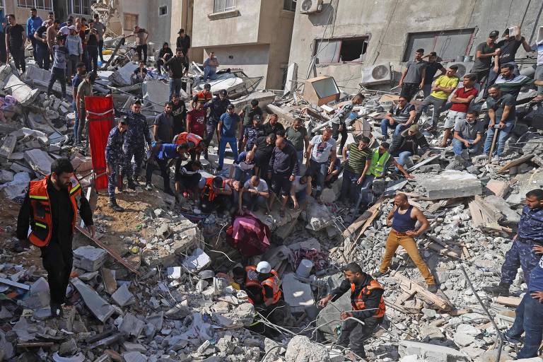 Paramédicos palestinos em Gaza buscam sobreviventes em meio a destroços de prédio atingido por bombardeio de Israel