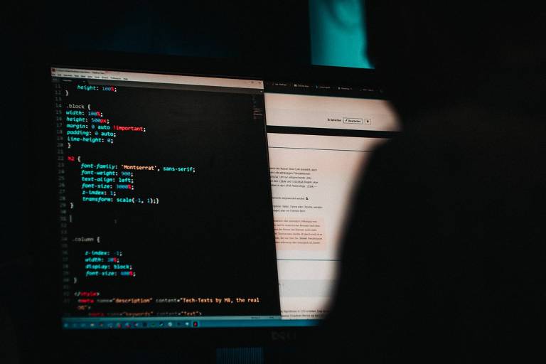 Imagem ilustrativa indica como funciona ataque hacker, no qual criminosos agem por meio de programas de computador. Silhueta de um homem encapuzado está à frente de um computador, com um prompt de programação na tela.