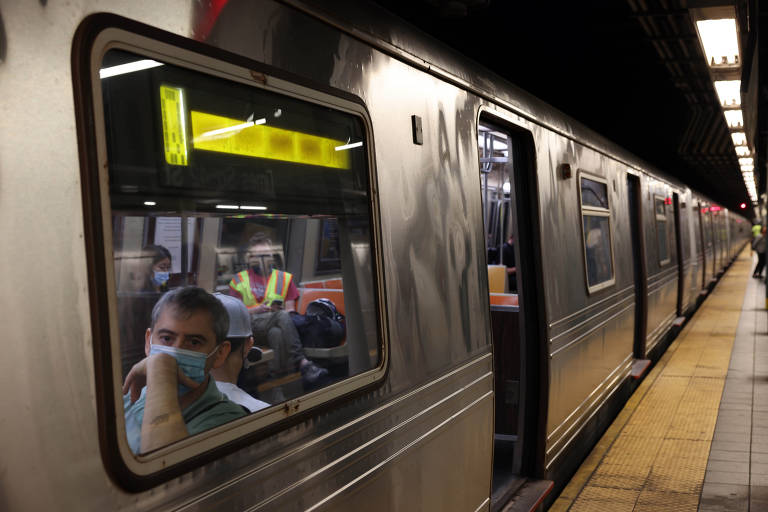 Passageiros com máscara no metrô de Nova York