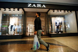 FILE PHOTO: A man walks past a Zara retail store, with its shutters drawn, at a mall in Caracas