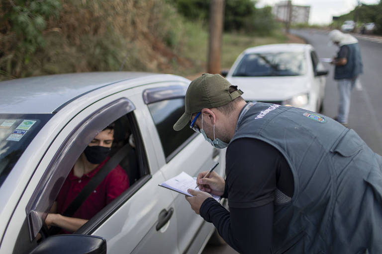 Imagem mostra agente conversando com motorista em barreira sanitária em Araraquara