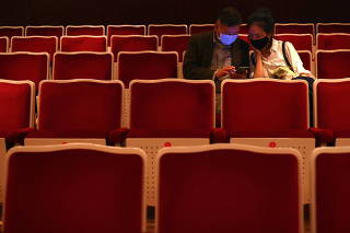 People wear protective masks to prevent the spread of the coronavirus disease (COVID-19) while using a mobile phone after attending a music concert at National Concert Hall in Taipei,