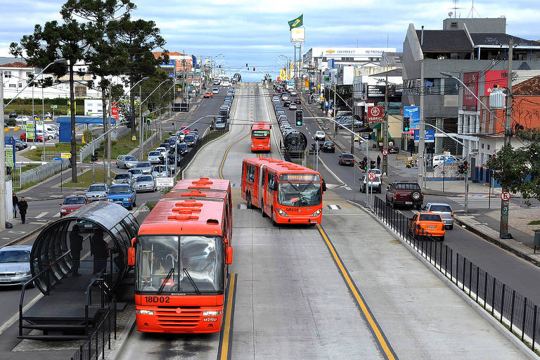 foto mostra um ônibus trafegando por corredor e um deles parado em estação