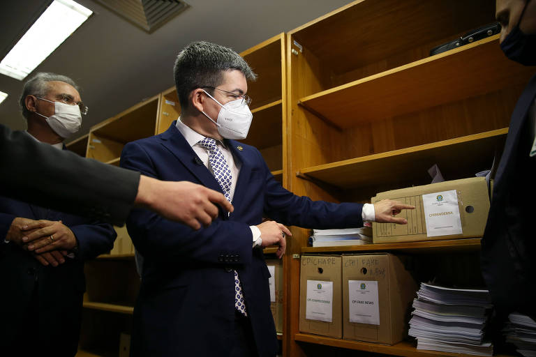 Homem de máscara aponta para caixa de documentos