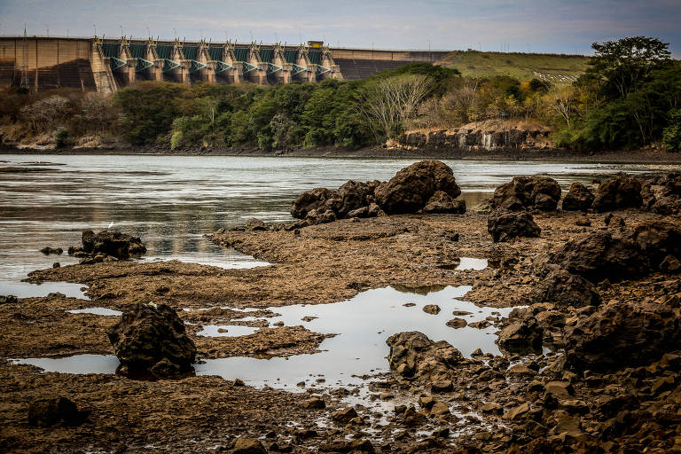 leito seco do rio com hidrelétrica ao fundo