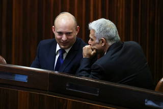 Yamina party leader Bennett smiles as he speaks to Yesh Atid party leader Lapid, during a special session of the Knesset whereby Israeli lawmakers elect a new president, at the plenum in the Knesset, Israel's parliament, in Jerusalem