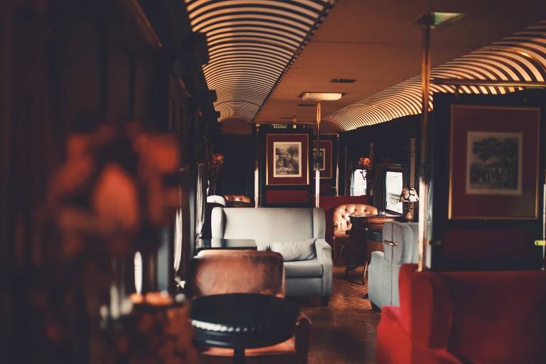 Imagem mostra interior de vagão de trem, com poltronas de luxo e quadros