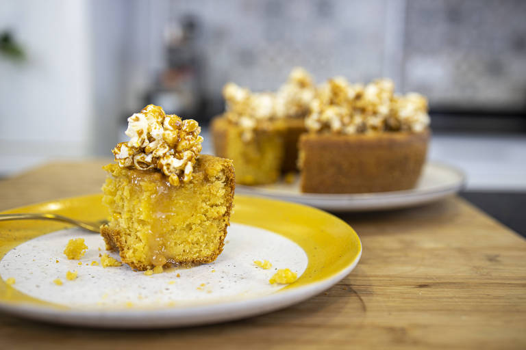 Fatia de bolo de milho sobre um garfo, apoiado em um prato amarelo e branco