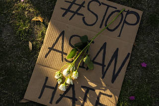 A flower is placed on a sign at a rally and vigil in Houston on March 20, 2021, after eight people, including six Asian women, were killed in a shooting spree at three massage parlors in the Atlanta area. (Go Nakamura/The New York Times)