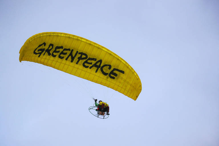 Ativista da organização não governamental Greenpeace, que atua em favor de causas de sustentabilidade, usa um parapente que traz a inscrição da ONG