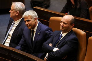 Israeli Prime minister Naftali Bennett, Foreign Minister Yair Lapid and Defence Minister Benny Gantz sit together following the vote on the new coalition at the Knesset, Israel's parliament, in Jerusalem
