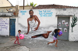 Girls play with balls in front of the graffiti made by artists in honor of Kathlen de Oliveira Romeu, who was pregnant and was shot dead during a police operation, according to local media, at the Lins slums complex in Rio de Janeiro