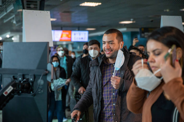 Pessoas tiram a máscara para fazer o reconhecimento facial para entrar no voo com destino ao Rio, no Aeroporto de Congonhas, em São Paulo