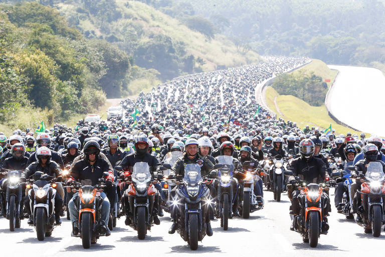 Bolsonaro a frente de uma motociata, com motoqueiros que ocupam toda a faixa de uma rodovia