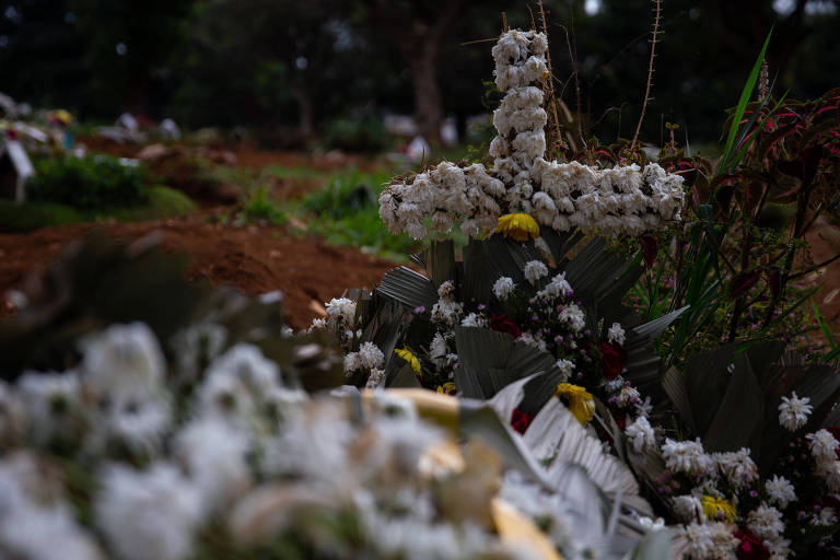 Imagem mostra uma cruz feita de flores em um túmulo