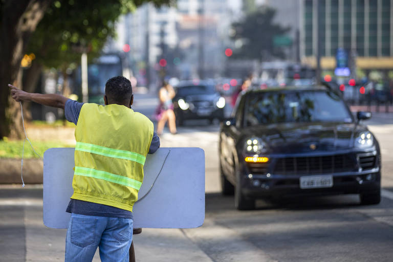 Homem negro com placa na av. Faria Lima; ciclovia escancara cor da desigualdade no Brasil