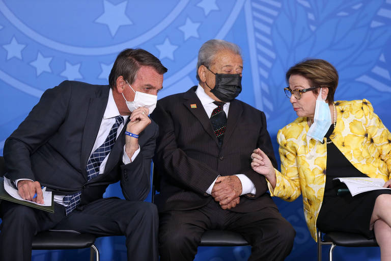 Dois homens e uma mulher sentados, conversando, com máscara