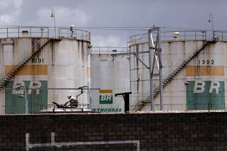 A worker checks the fuel volumes on a train wagon near a tank of Brazil's state-run Petrobras oil company in Brasilia