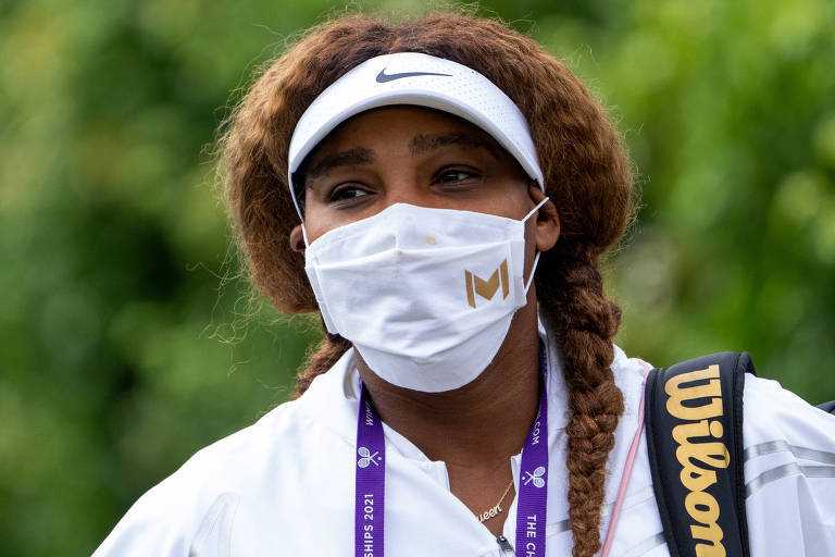 Serena Williams com máscara e agasalho branco