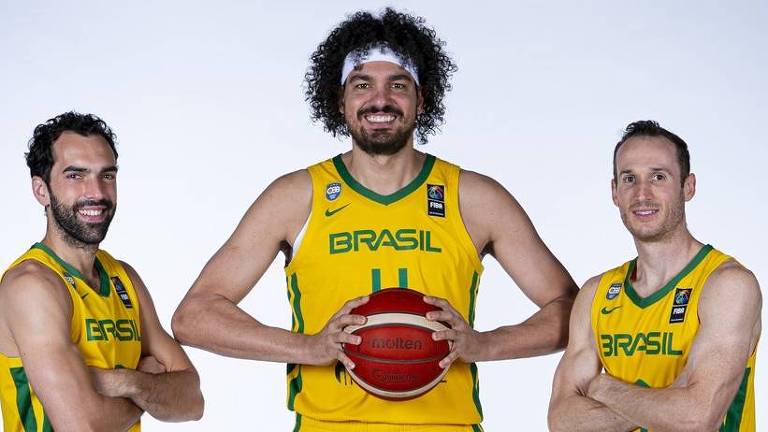 Jogadores posam com uniforme da seleção; ao centro, Varejão segura uma bola de basquete