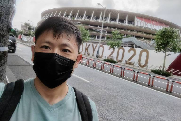 Homem de máscara tira selfie em frente a estádio