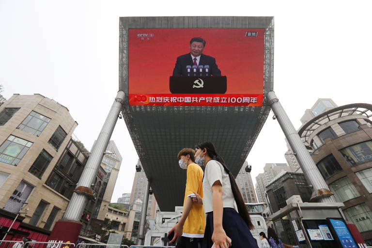 Telão na rua, em Pequim, transmite evento de entrega de medalhas que integra celebrações do centenário