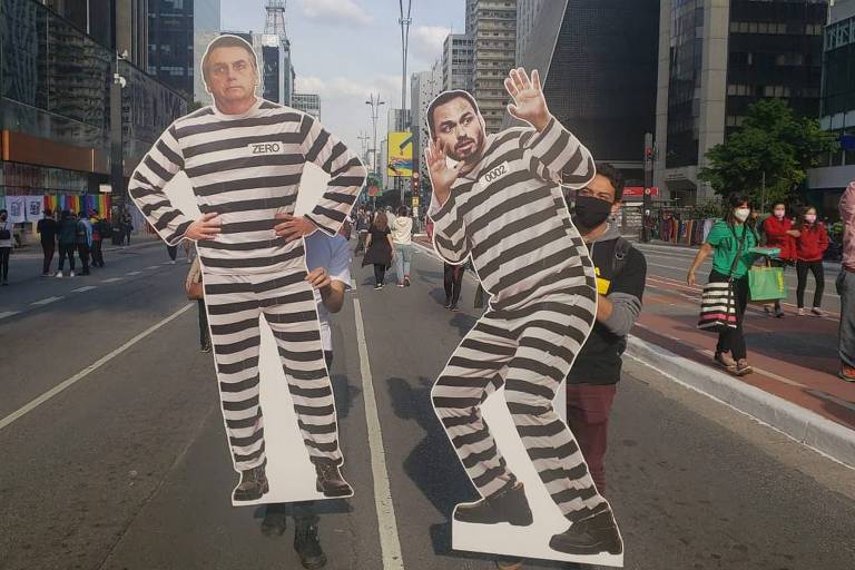 Manifestantes exibem figuras de papelão representando Bolsonaro e seu filho Carlos em trajes de prisão durante protesto na avenida Paulista, em São Paulo