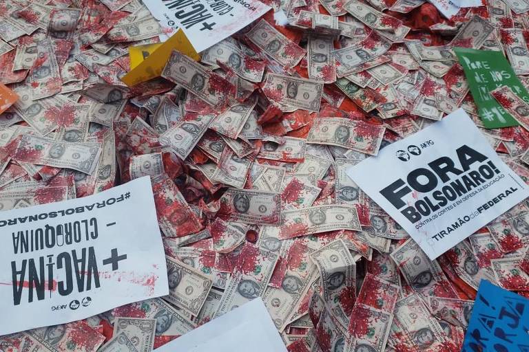Manifestantes em São Paulo espalham réplicas de notas de US$ 1 estampadas com o rosto de Bolsonaro e manchadas de vermelho cor de sangue, em referência à denúncia de pedido de propina de US$ 1 por dose de vacina negociada com o Ministério da Saúde, revelado em reportagem da Folha