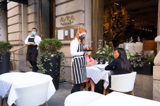 Mask-free patrons order from a masked waiter at Nello Restaurant in New York, June 23, 2021. (Sara Messinger/The New York Times)
