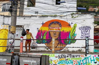 A woman throws garbage next to a graffiti made by artists in honor of Kathlen de Oliveira Romeu, who was pregnant and was shot dead during a police operation, according to local media, at the Lins slums complex in Rio de Janeiro