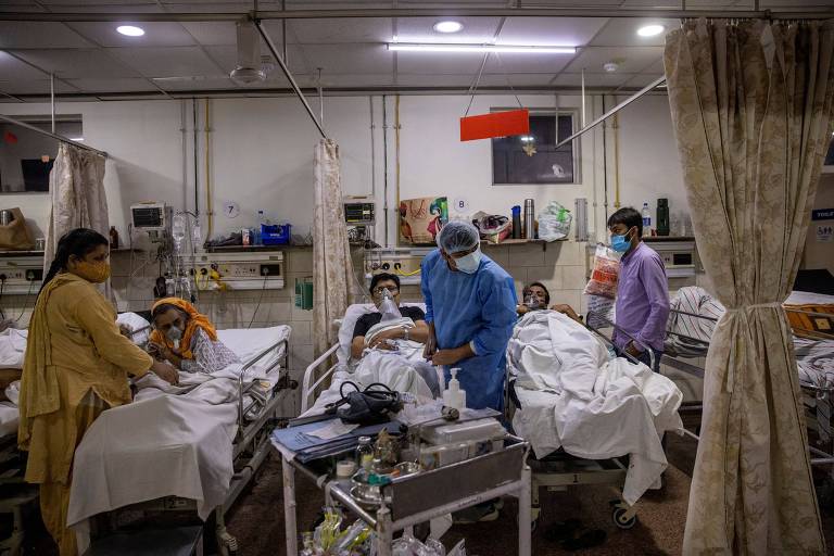 Médico (centro) trata pacientes com Covid-19 em hospital de Nova Déli, na Índia