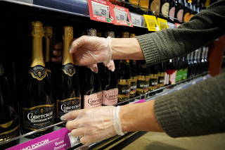 An employee arranges bottles of Russian sparkling wine at a supermarket in Moscow