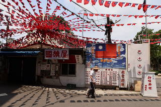 A man walks by a restaurant decorated with Taiwan flags in Taoyuan