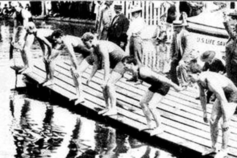 Nadadores se preparam para a largada de uma prova na balsa improvisada no lago artificial dos Jogos Olímpicos de Saint Louis, em 1904; o evento foi dominado pelos atletas da casa, que eram maioria absoluta