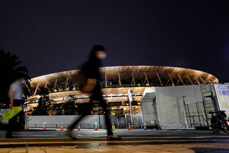 Pedestre passa em frente a Estádio Nacional, local da cerimônia de abertura da Olimpíada de Tóquio