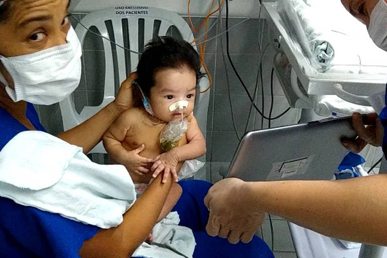 Em hospital, enfermeiras seguram bebê em frente a tablet para ver a mãe
