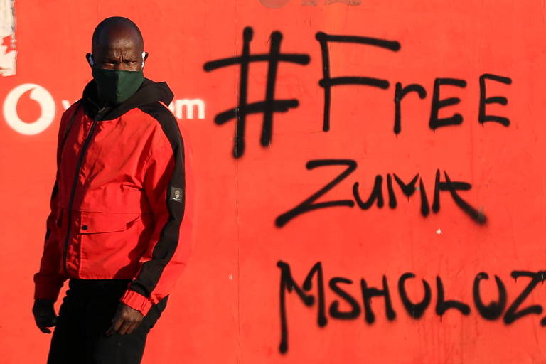 Homem em frente a grafite com as palavras "Zuma livre" em Vosloorus, na África do Sul