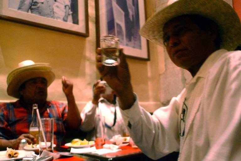 Homens mexicanos bebem mezcal em um bar de Oaxaca, em 2004