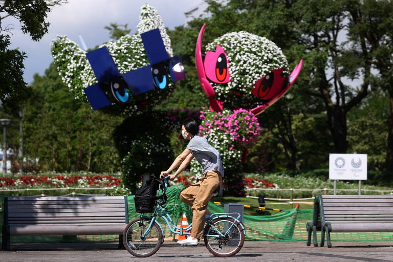Ciclista passa por esculturas das mascotes em rua de Tóquio