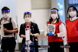 FILE PHOTO: Staff wearing face masks and shields wait for the arrival of foreign athletes at Haneda Airport ahead of Tokyo 2020 Olympic Games, in Tokyo