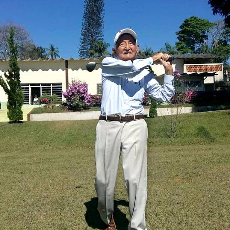 homem idoso joga golfe em campo ensolarado e florido 