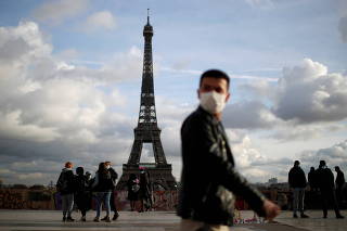 FILE PHOTO: People wear protective face masks in Paris